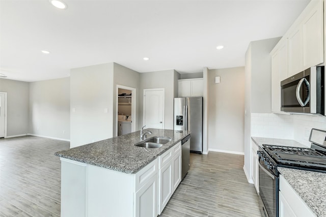 25707 Boxwood Hedge Ln, Tomball, TX 77375 - kitchen with appliances with stainless steel finishes, light wood finished floors, stone counters, a kitchen island with sink, and recessed lighting