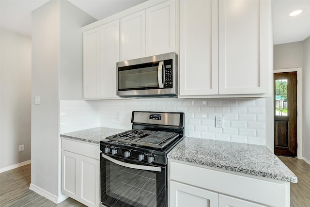 25707 Boxwood Hedge Ln, Tomball, TX 77375 - kitchen with stainless steel appliances, light stone counters, light wood-style floors, and white cabinetry