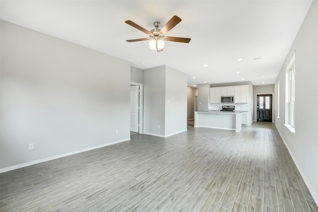 25707 Boxwood Hedge Ln, Tomball, TX 77375 - unfurnished living room featuring light wood-style flooring, a ceiling fan, and recessed lighting