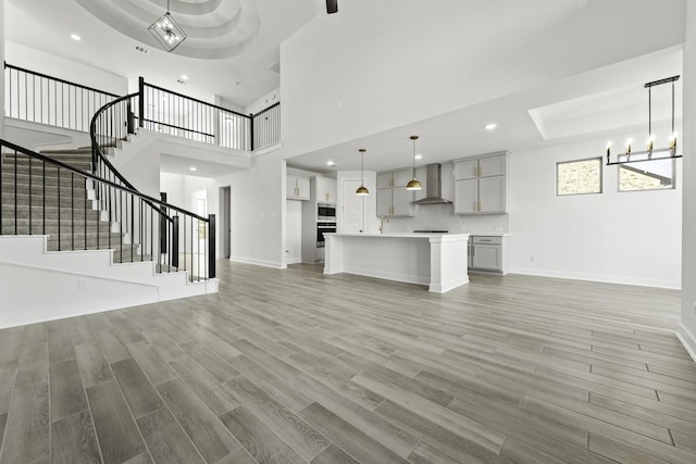 5021 Steady Breeze Dr, Katy, TX 77493 - unfurnished living room with stairs, light wood-style flooring, a chandelier, recessed lighting, and a high ceiling