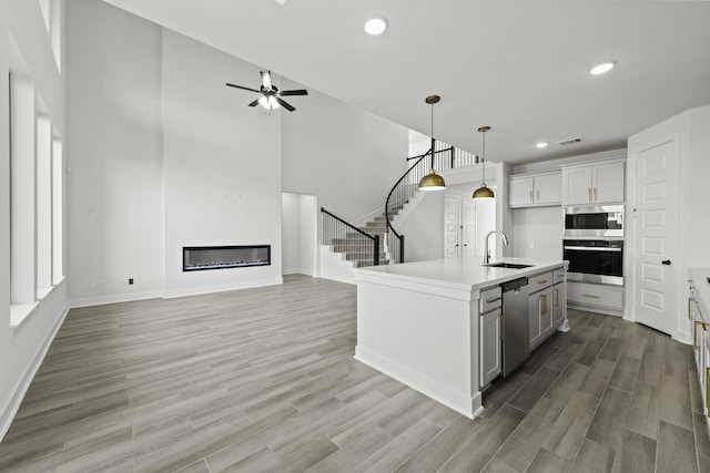 5021 Steady Breeze Dr, Katy, TX 77493 - kitchen featuring stainless steel appliances, a glass covered fireplace, light wood-type flooring, light countertops, and recessed lighting