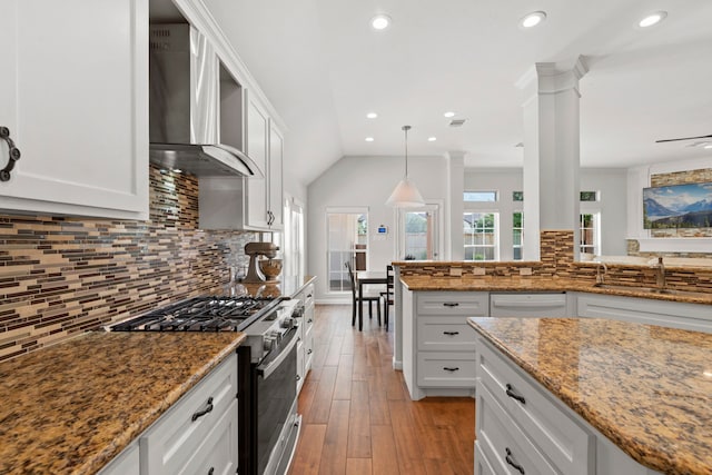 21403 Wild Jasmine Ln, Katy, TX 77450 - kitchen with gas range, wall chimney range hood, ornate columns, light wood-style floors, and backsplash