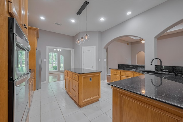 6210 Mahogany Way, Magnolia, TX 77354 - kitchen featuring a center island, appliances with stainless steel finishes, light tile patterned flooring, arched walkways, and decorative light fixtures