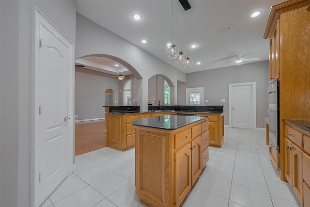 6210 Mahogany Way, Magnolia, TX 77354 - kitchen featuring arched walkways, a ceiling fan, a kitchen island, light tile patterned floors, and recessed lighting