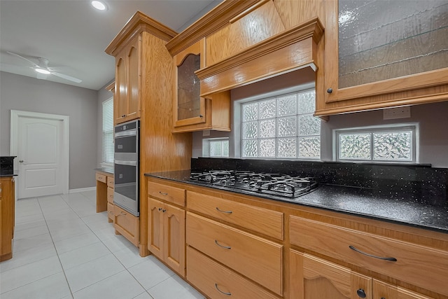 6210 Mahogany Way, Magnolia, TX 77354 - kitchen with black gas cooktop, double oven, light tile patterned floors, ceiling fan, and glass insert cabinets