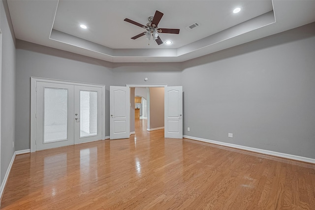 6210 Mahogany Way, Magnolia, TX 77354 - spare room with ceiling fan, a tray ceiling, light wood-style floors, arched walkways, and french doors
