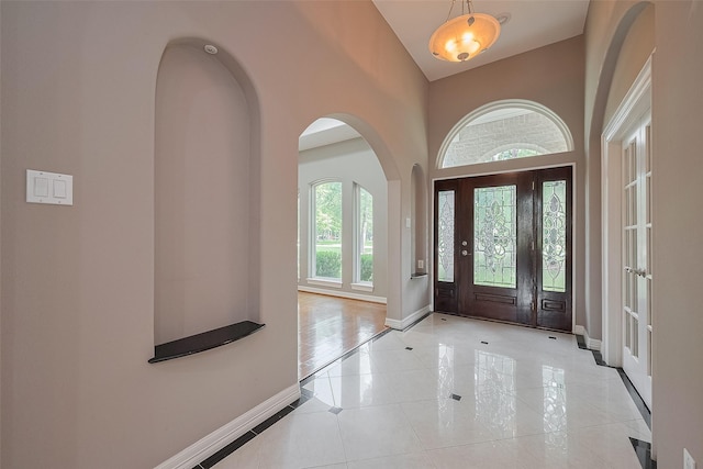 6210 Mahogany Way, Magnolia, TX 77354 - entryway featuring inlaid floor details, light tile patterned flooring, arched walkways, and high vaulted ceiling