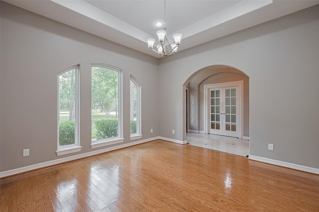 6210 Mahogany Way, Magnolia, TX 77354 - spare room with arched walkways, a chandelier, french doors, wood finished floors, and a tray ceiling