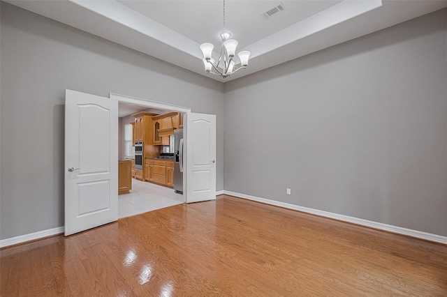6210 Mahogany Way, Magnolia, TX 77354 - empty room with light wood-type flooring, a chandelier, and a tray ceiling