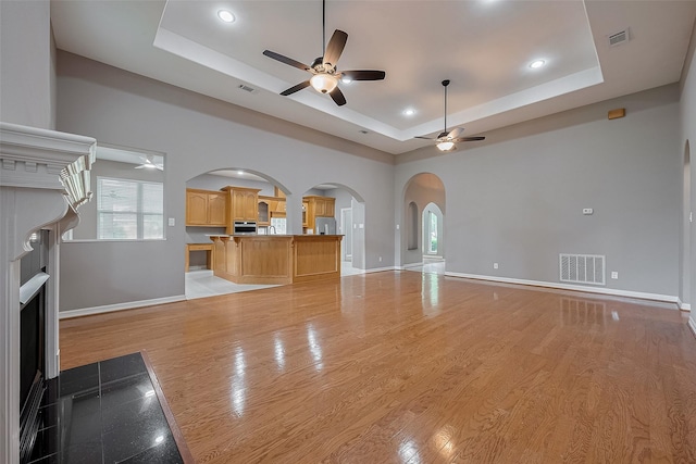 6210 Mahogany Way, Magnolia, TX 77354 - unfurnished living room with a tray ceiling, ceiling fan, arched walkways, a fireplace, and recessed lighting