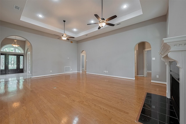6210 Mahogany Way, Magnolia, TX 77354 - unfurnished living room with arched walkways, a raised ceiling, wood finished floors, a high ceiling, and recessed lighting