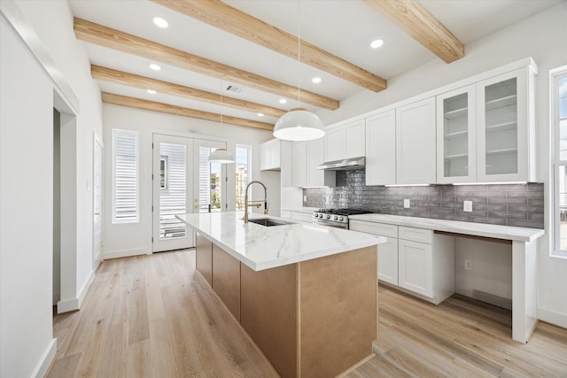 2221 Bevis St, Houston, TX 77008 - kitchen featuring under cabinet range hood, decorative backsplash, light wood-style flooring, beam ceiling, and light stone countertops
