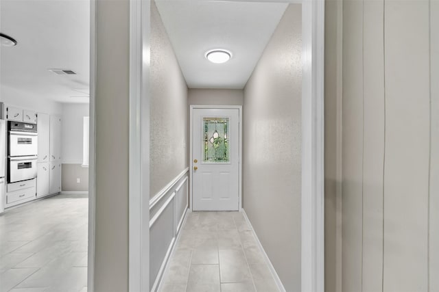 21807 Glenbranch Dr, Spring, TX 77388 - doorway to outside with light tile patterned flooring, a textured wall, wainscoting, and a decorative wall