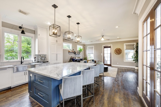 818 Waverly St, Houston, TX 77007 - kitchen with white cabinetry, a center island, ornamental molding, open floor plan, and plenty of natural light