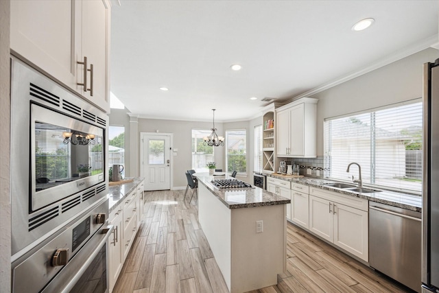 5602 Bergenfield Ct, Katy, TX 77450 - kitchen with appliances with stainless steel finishes, a chandelier, a center island, white cabinets, and light stone counters