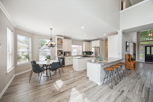 5602 Bergenfield Ct, Katy, TX 77450 - kitchen featuring stainless steel fridge, a chandelier, ornamental molding, light wood-type flooring, and a center island