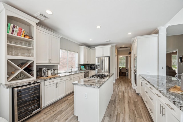 5602 Bergenfield Ct, Katy, TX 77450 - kitchen featuring beverage cooler, appliances with stainless steel finishes, a center island, white cabinetry, and recessed lighting