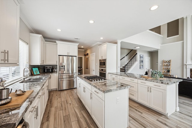 5602 Bergenfield Ct, Katy, TX 77450 - kitchen with appliances with stainless steel finishes, crown molding, a center island, recessed lighting, and light wood-style floors