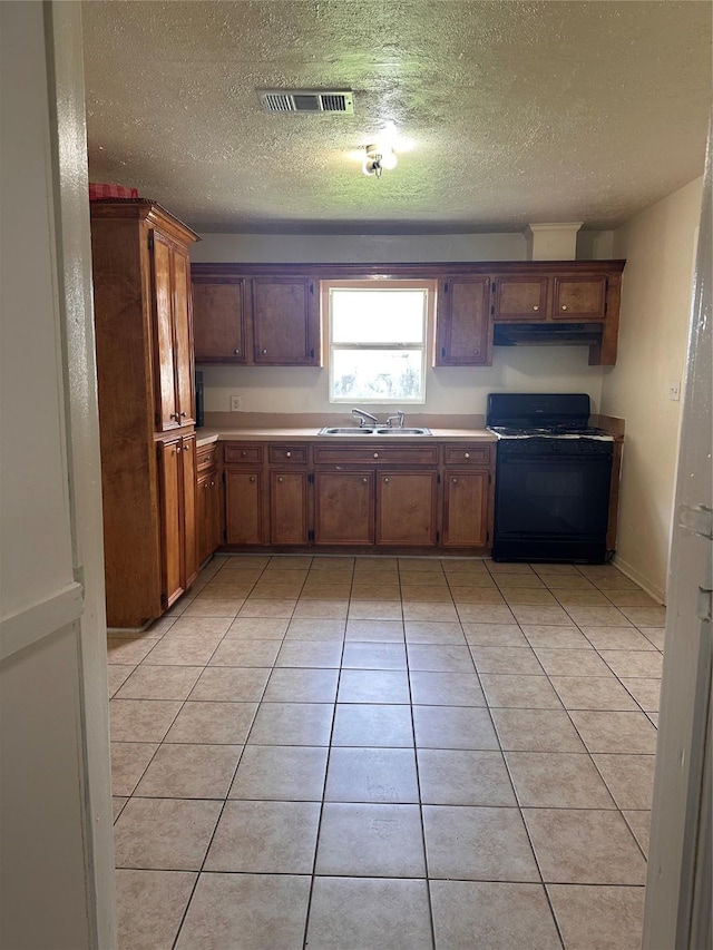 2122 Kowis St, Houston, TX 77093 - kitchen with black range with gas cooktop, under cabinet range hood, a textured ceiling, light tile patterned floors, and light countertops
