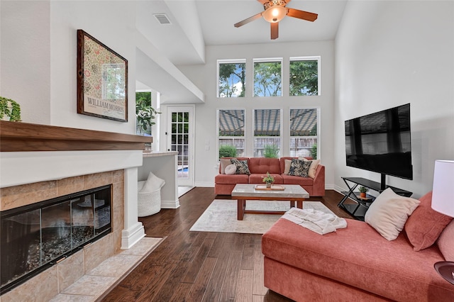 135 Wisteria Walk Cir, The Woodlands, TX 77381 - living area featuring dark wood-style flooring, a ceiling fan, a tiled fireplace, and a towering ceiling