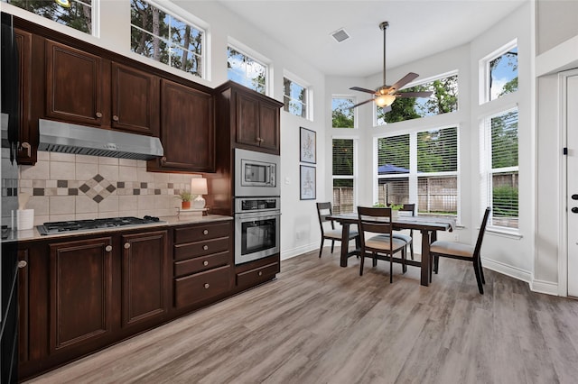 135 Wisteria Walk Cir, The Woodlands, TX 77381 - kitchen featuring stainless steel appliances, under cabinet range hood, ceiling fan, tasteful backsplash, and light wood-style flooring