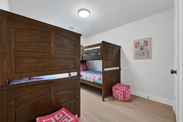 135 Wisteria Walk Cir, The Woodlands, TX 77381 - bedroom with light wood-style flooring and a textured ceiling