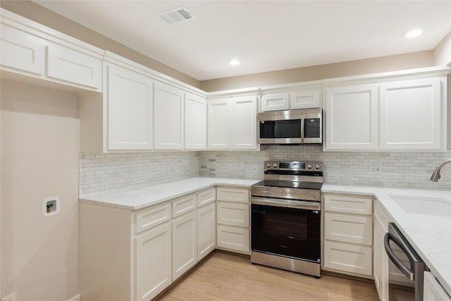 3802 Knollcrest Dr, Montgomery, TX 77356 - kitchen with appliances with stainless steel finishes, light stone countertops, light wood-type flooring, decorative backsplash, and white cabinets