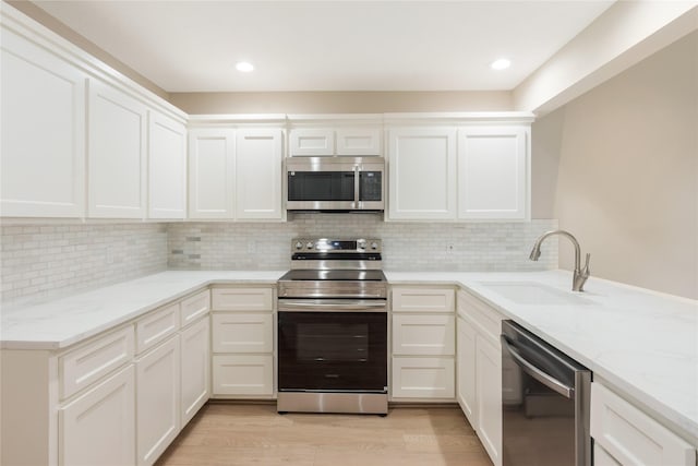 3802 Knollcrest Dr, Montgomery, TX 77356 - kitchen featuring appliances with stainless steel finishes, light wood-style floors, light stone countertops, and white cabinets
