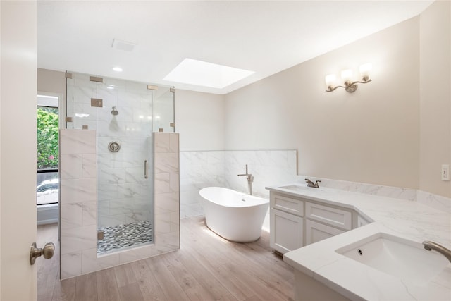 3802 Knollcrest Dr, Montgomery, TX 77356 - bathroom with two vanities, a stall shower, a skylight, a freestanding tub, and wood finished floors