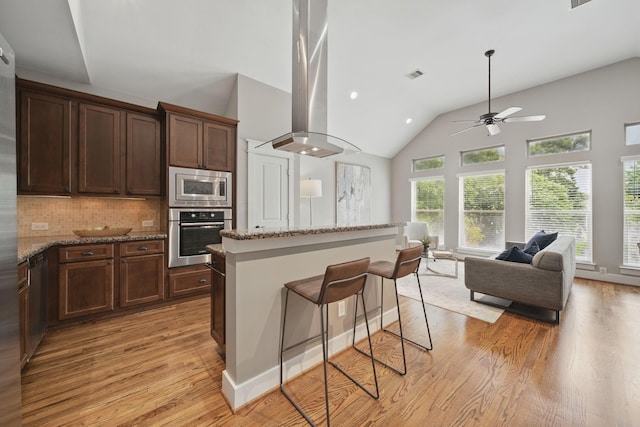 1028 Dunbar St, Houston, TX 77009 - kitchen with appliances with stainless steel finishes, light wood-style flooring, ceiling fan, island range hood, and open floor plan
