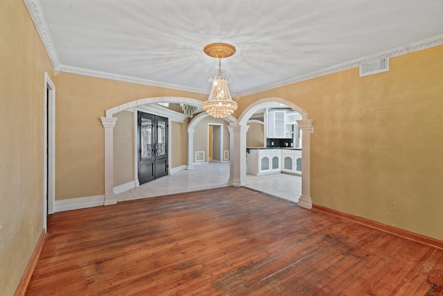 7847 Broadview Dr, Houston, TX 77061 - unfurnished room with arched walkways, decorative columns, a chandelier, wood-type flooring, and crown molding