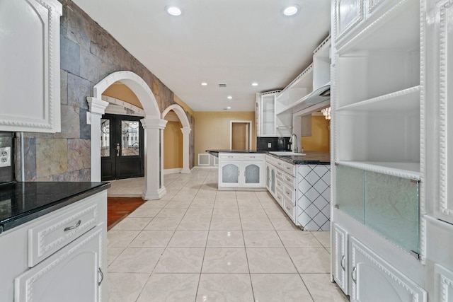 7847 Broadview Dr, Houston, TX 77061 - kitchen featuring decorative columns, open shelves, light tile patterned floors, dark countertops, and arched walkways