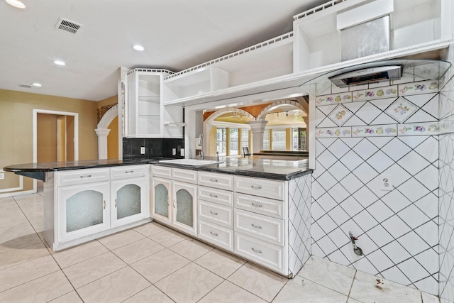 7847 Broadview Dr, Houston, TX 77061 - kitchen with ornate columns, a peninsula, open shelves, light tile patterned floors, and recessed lighting