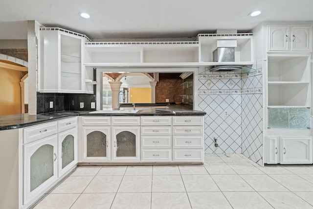 7847 Broadview Dr, Houston, TX 77061 - kitchen with open shelves, decorative columns, light tile patterned floors, dark countertops, and white cabinets