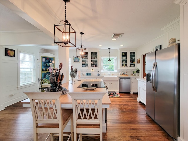 505 S Jackson St, Brenham, TX 77833 - kitchen with appliances with stainless steel finishes, crown molding, glass insert cabinets, light countertops, and decorative backsplash