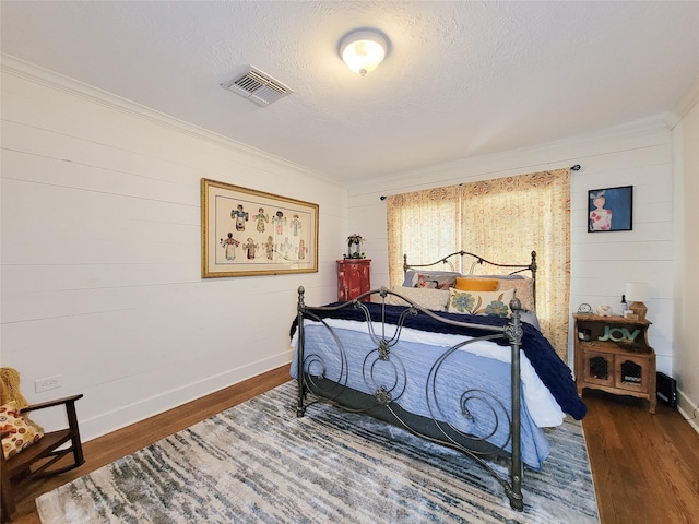 505 S Jackson St, Brenham, TX 77833 - bedroom featuring wood finished floors, crown molding, a textured ceiling, and wooden walls