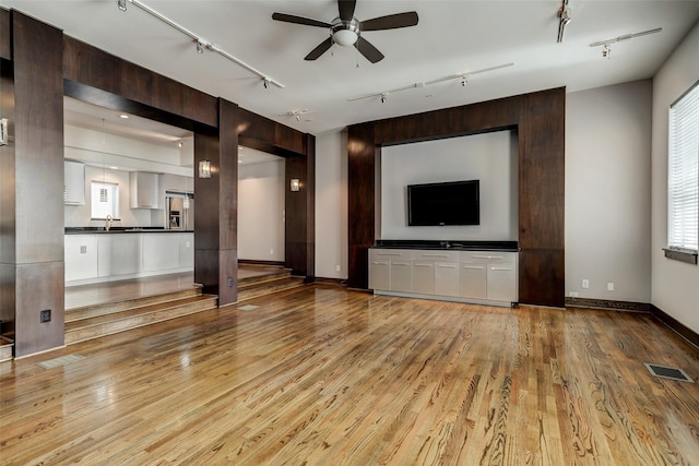 1820 Prospect St, Houston, TX 77004 - unfurnished living room with rail lighting, ceiling fan, and light wood-style flooring