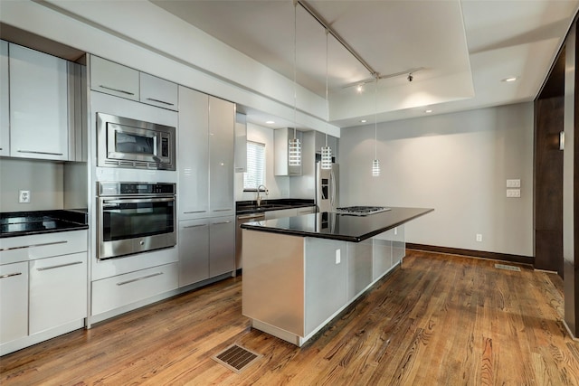 1820 Prospect St, Houston, TX 77004 - kitchen with stainless steel appliances, dark countertops, track lighting, and wood finished floors