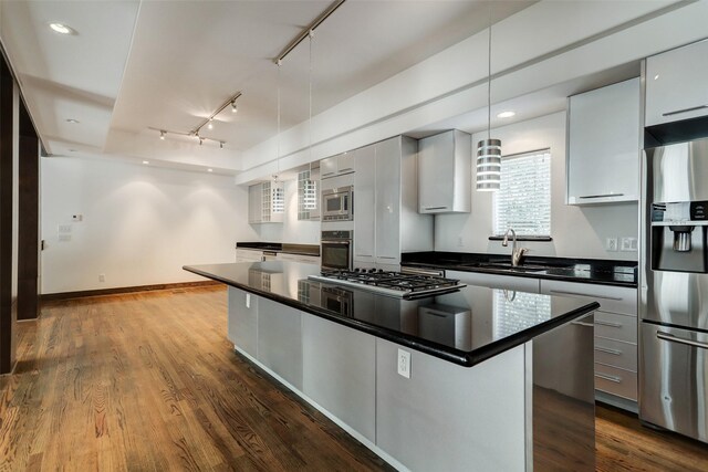 1820 Prospect St, Houston, TX 77004 - kitchen with appliances with stainless steel finishes, track lighting, dark countertops, a kitchen island, and dark wood finished floors