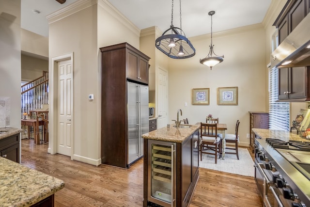5023 La Branch St, Houston, TX 77004 - kitchen with ventilation hood, wine cooler, an island with sink, appliances with stainless steel finishes, and dark brown cabinets