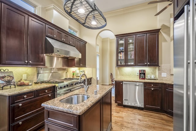 5023 La Branch St, Houston, TX 77004 - kitchen with appliances with stainless steel finishes, under cabinet range hood, arched walkways, ornamental molding, and glass insert cabinets
