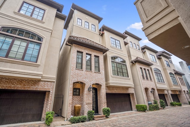 5023 La Branch St, Houston, TX 77004 - mediterranean / spanish-style home with brick siding, stucco siding, a garage, and decorative driveway