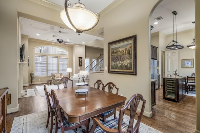 5023 La Branch St, Houston, TX 77004 - dining area with beverage cooler, ornamental molding, ceiling fan, dark wood-style floors, and arched walkways