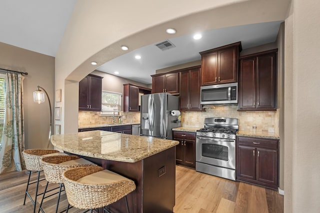 6619 Crystal Forest Trl, Katy, TX 77493 - kitchen featuring stainless steel appliances, healthy amount of natural light, a breakfast bar area, light stone counters, and recessed lighting