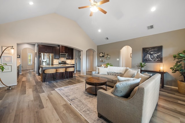6619 Crystal Forest Trl, Katy, TX 77493 - living area with arched walkways, ceiling fan, light wood finished floors, high vaulted ceiling, and recessed lighting