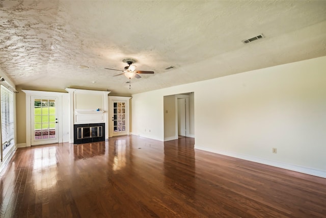 101 Fairway View Ln, Montgomery, TX 77356 - unfurnished living room with wood finished floors, a ceiling fan, a glass covered fireplace, and a textured ceiling