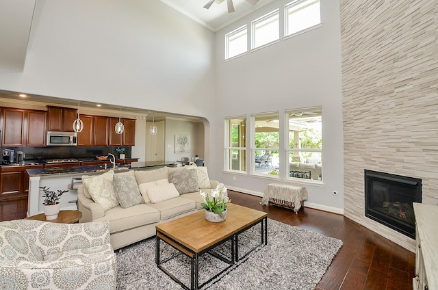 25718 Creek Ledge Dr, Katy, TX 77494 - living room with a high ceiling, a tiled fireplace, crown molding, dark wood finished floors, and ceiling fan