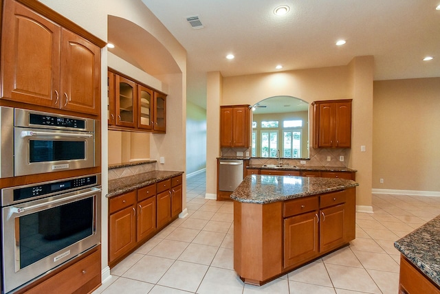 9610 Oakland Lake Way, Missouri City, TX 77459 - kitchen featuring appliances with stainless steel finishes, dark stone counters, brown cabinetry, and recessed lighting