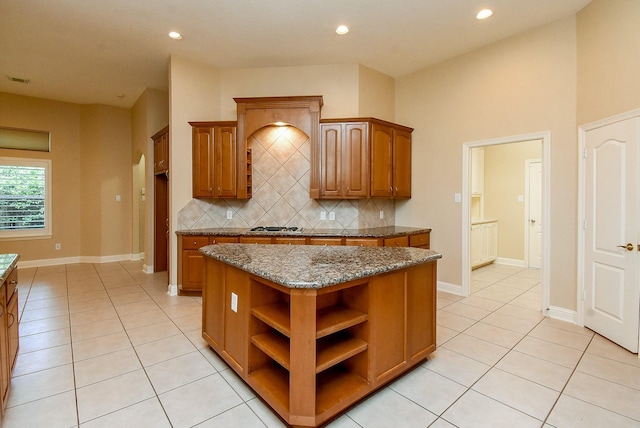 9610 Oakland Lake Way, Missouri City, TX 77459 - kitchen with light tile patterned floors, tasteful backsplash, brown cabinetry, dark stone countertops, and a kitchen island