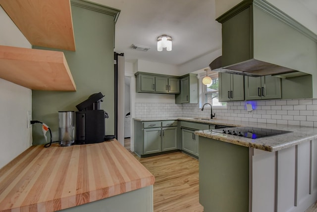 510 Daffodil St, Lake Jackson, TX 77566 - kitchen featuring green cabinetry, black electric stovetop, exhaust hood, a peninsula, and backsplash